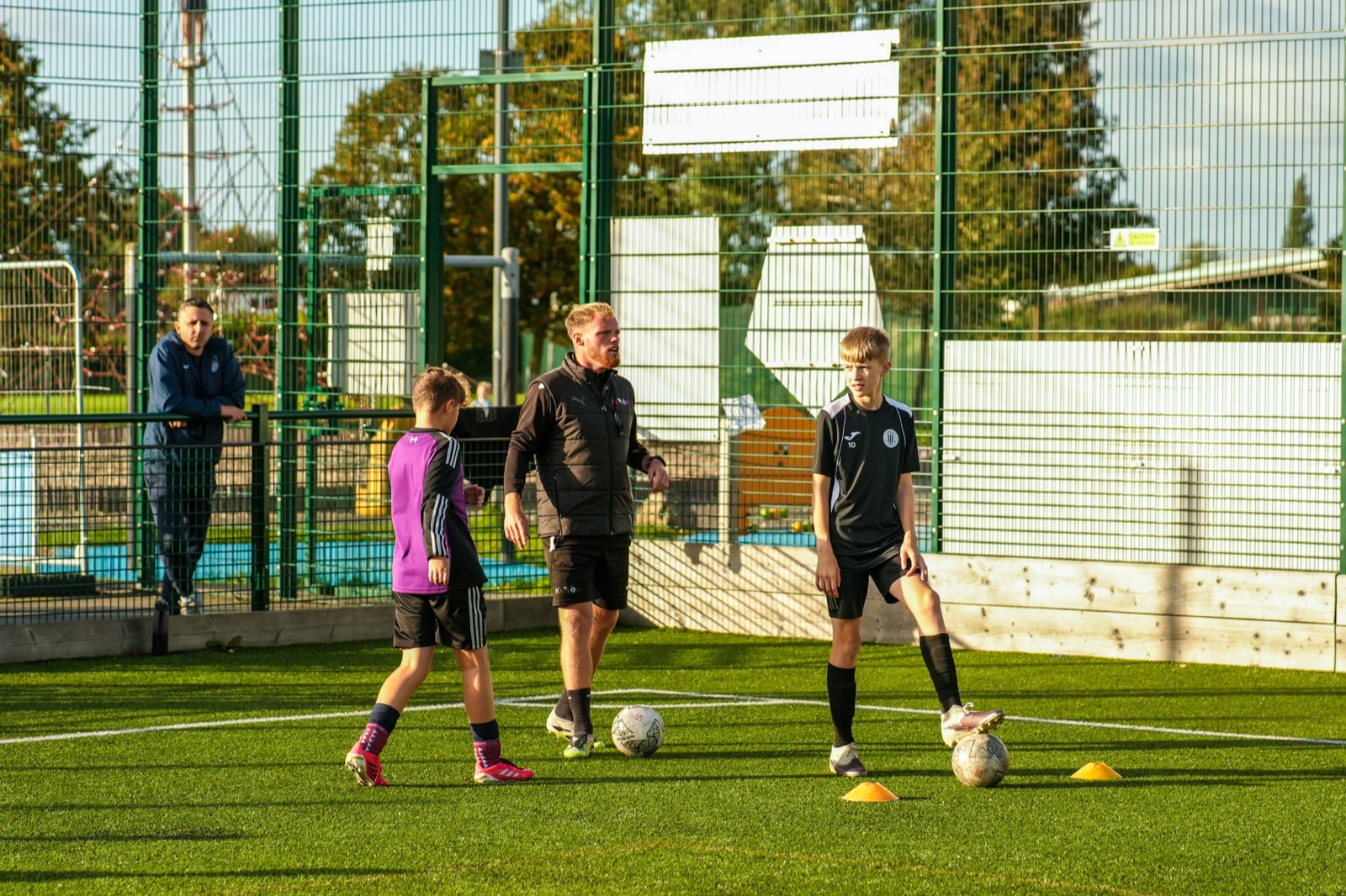 A Kick On coach leading a cones drill with two young players