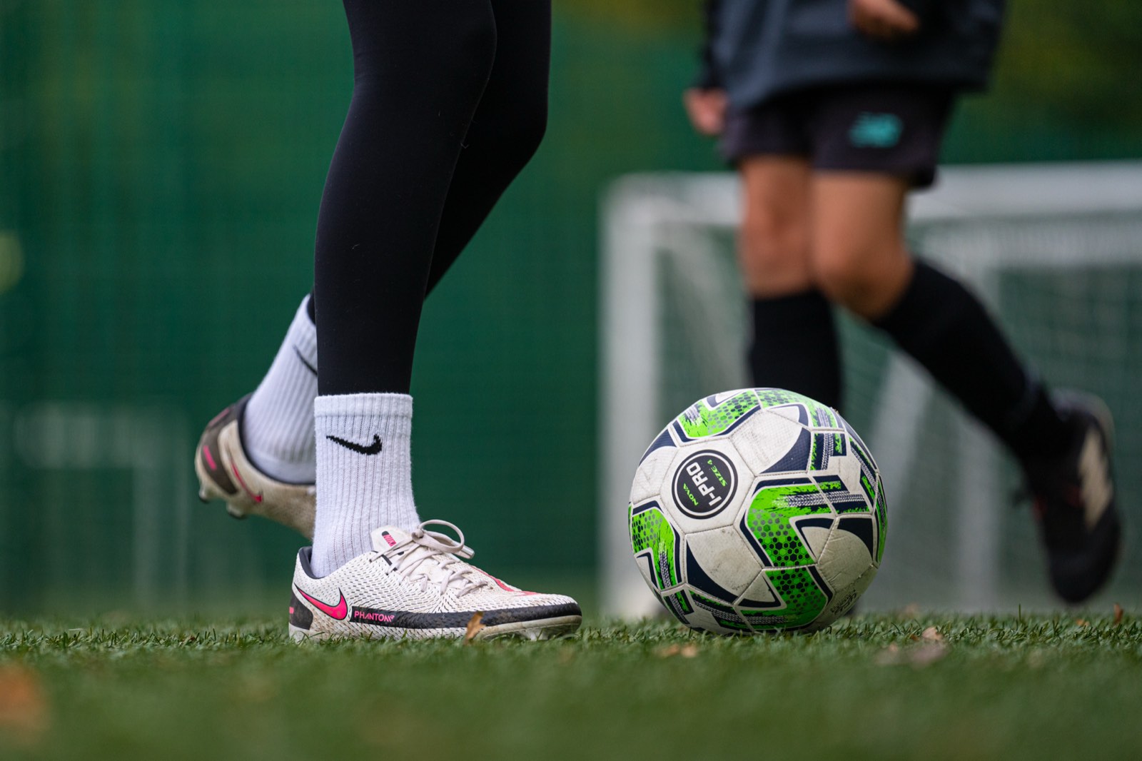 Close-up of a young player's boots on the ball