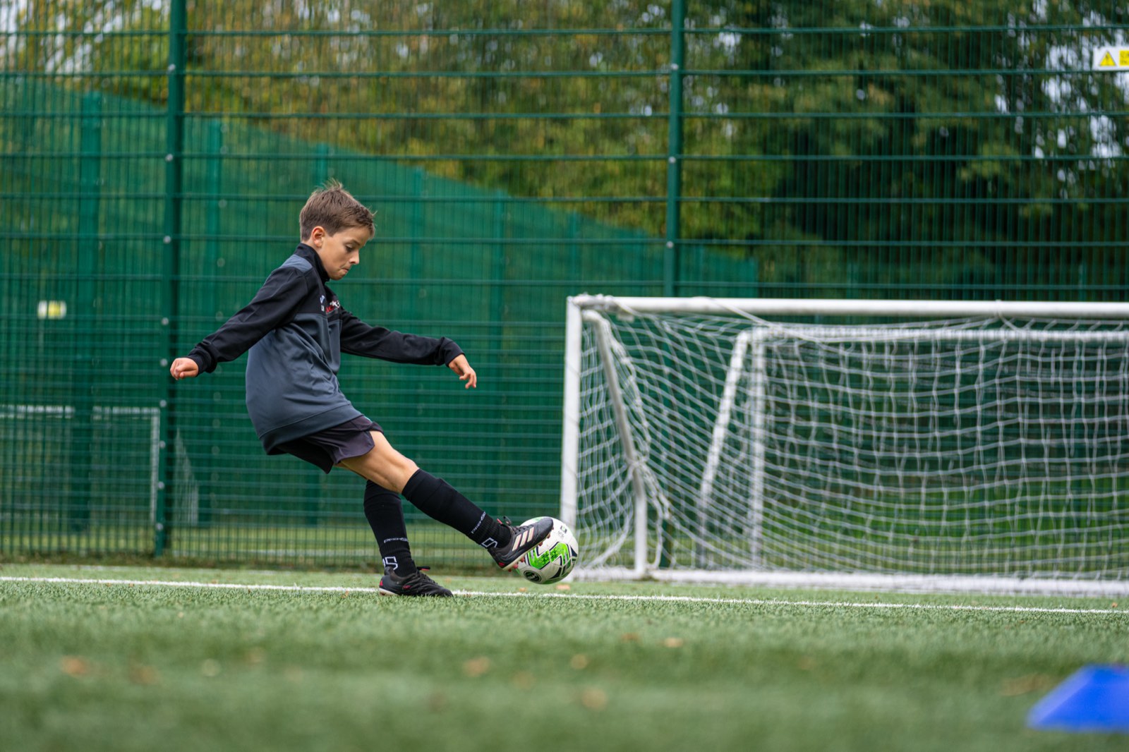 Young player striking towards goal during a session